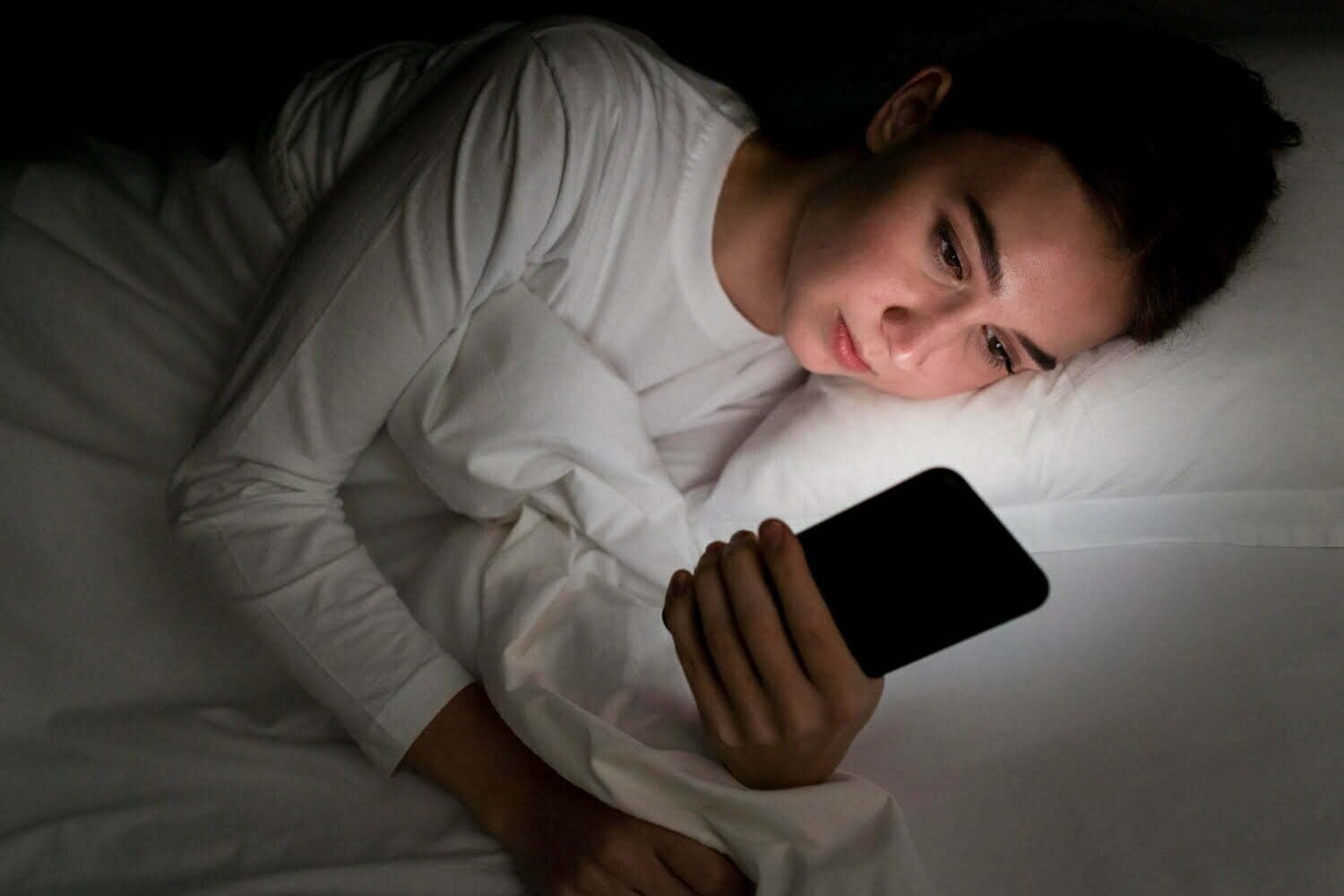 foto de chica de noche en la cama con teléfono