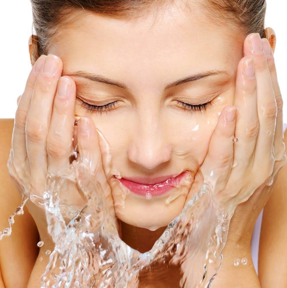 Mujer lavando su cara con agua helada