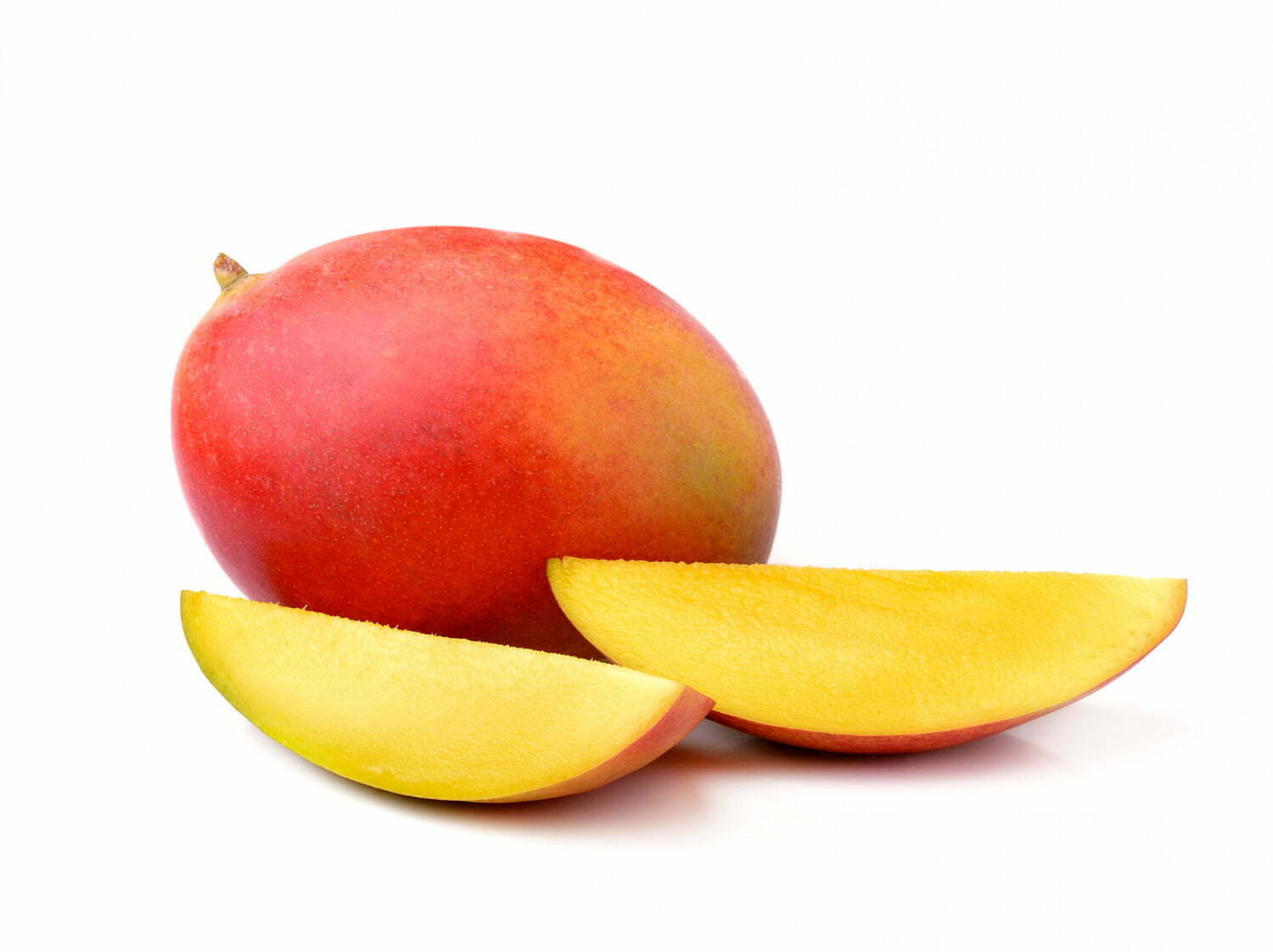 Foto de mango entero junto a pedazos de mango, sobre fondo blanco