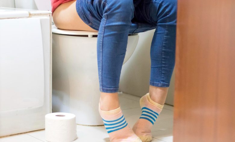foto de mujer con diarrea sentada en el inodoro con los pantalones abajo