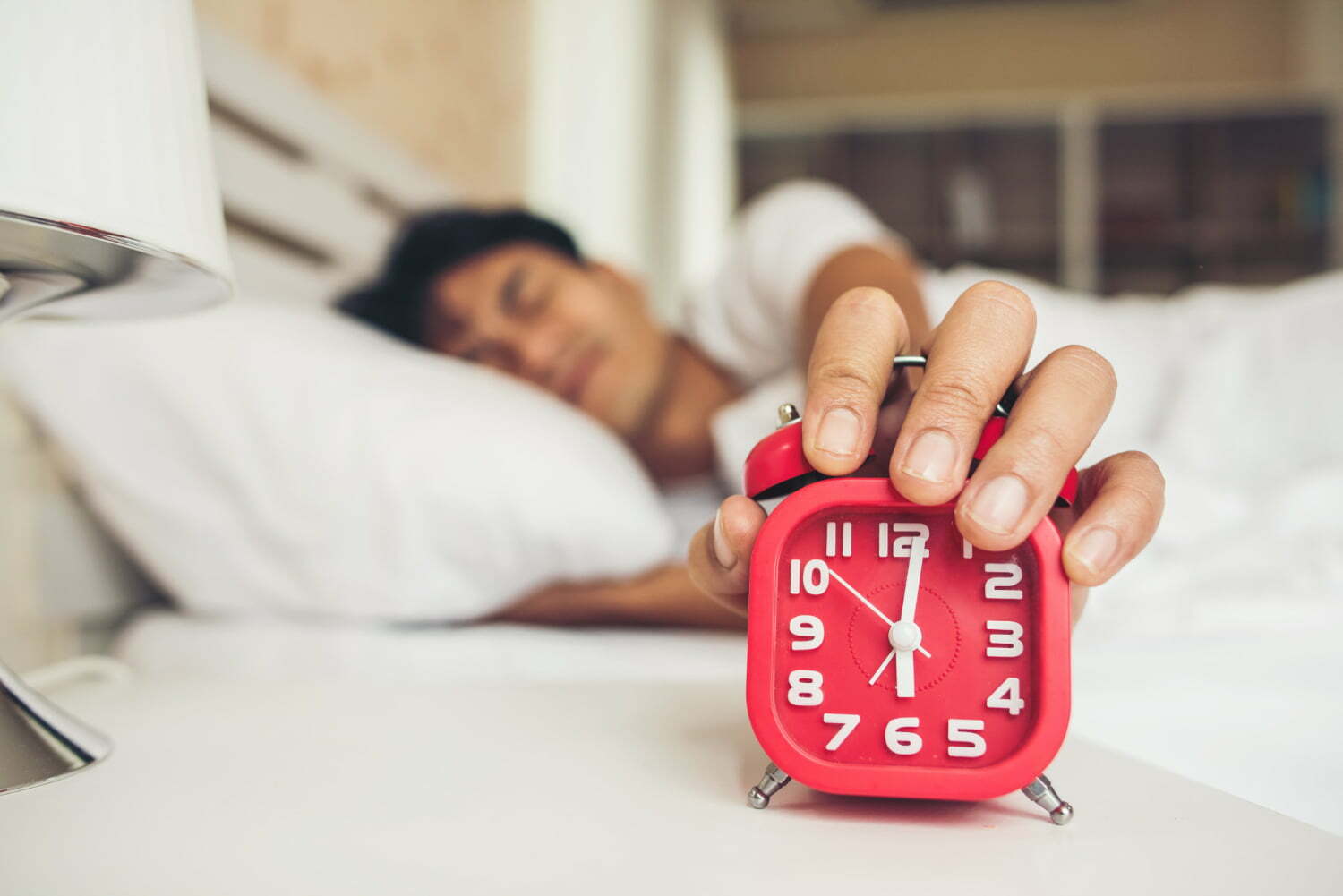 hombre que le cuesta levantarse temprano apagando el despertador - Ocho señales de alarma que nos da el cuerpo al levantarnos y no debemos ignorar / rutina