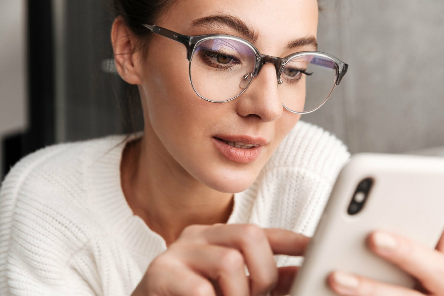 Mujer viendo su celular con gafas para proteger sus ojos / nomofobia / apego ansioso / celular