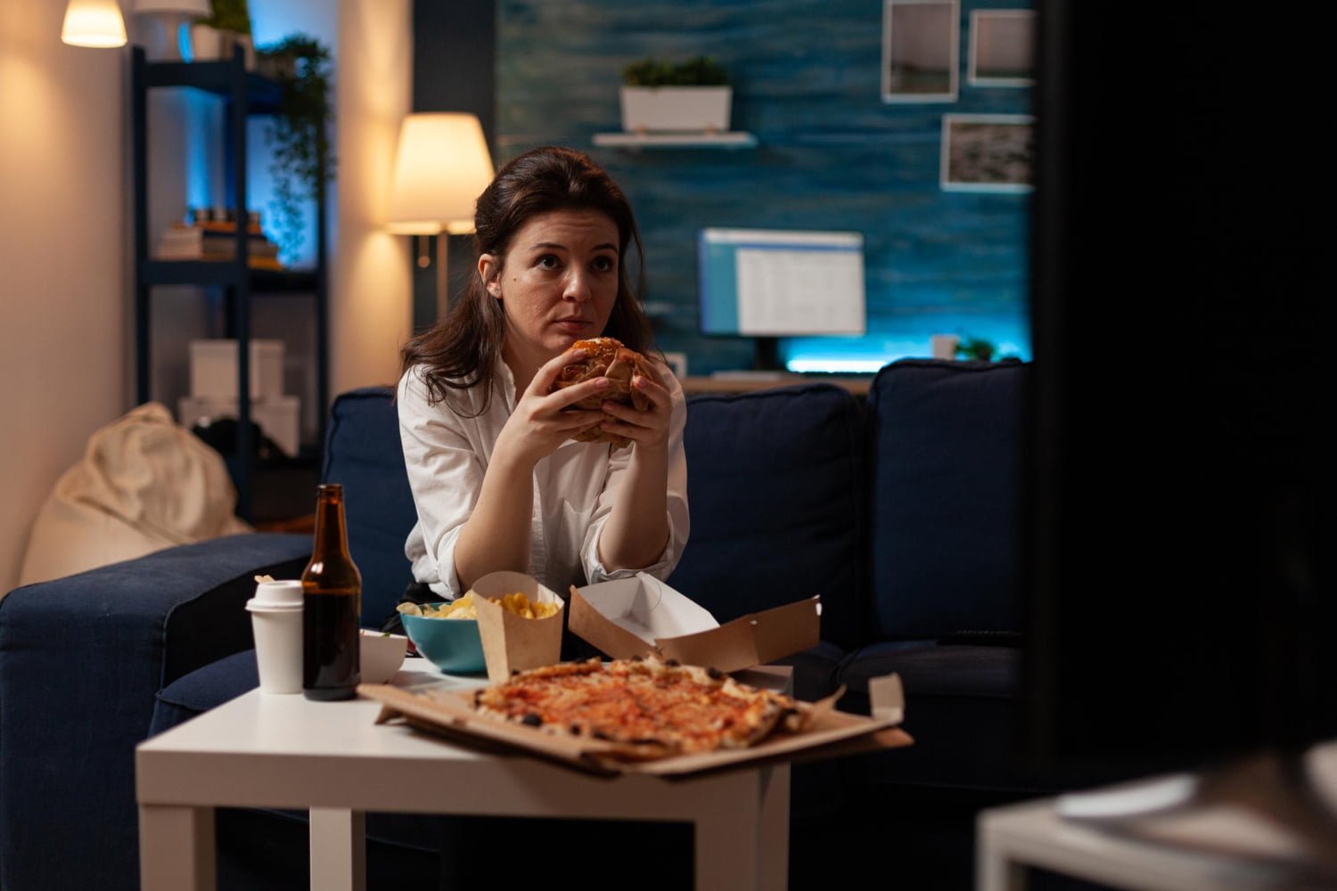 Mujer que acostumbra a Ver televisión mientras come / pizza / alimentos / canas